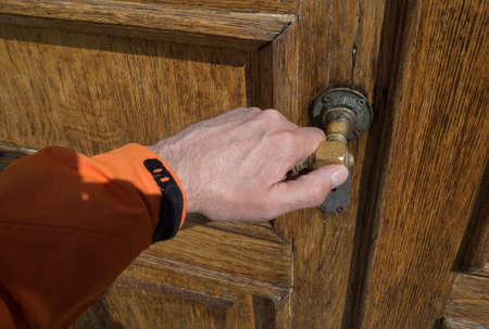 Hand on a handle wooden door to open or close it.の写真素材