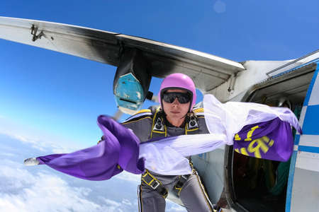 The girl parachutist jumps out of an airplane with a flag の写真素材