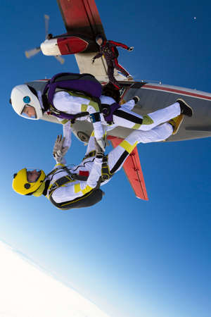 Three parachutists jumping out of an airplane in free style.の写真素材