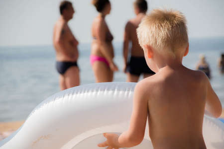 A boy runs along the sandy beach to swim in the seaの写真素材