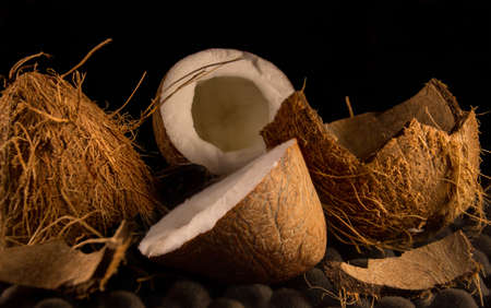 Coconut fruit - on a dark background, chopped pieces of shell and a white slice of pulp.の写真素材