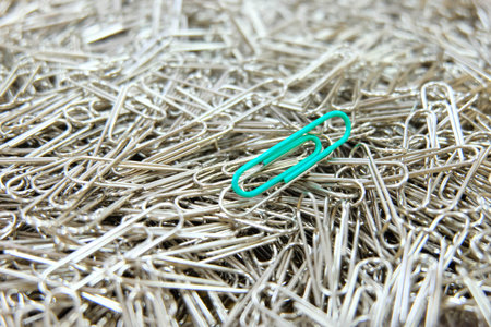 Green paper clip on multiple paper clips background.の写真素材