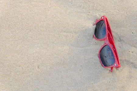 A red sun glasses at the beach,A red sun glasses on the sand.