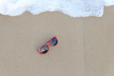 Red sunglasses on the sand at the beach, summer timeの写真素材