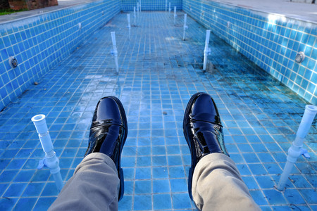 man black leather shoe with brown jeans lower legs into a dry poolの写真素材