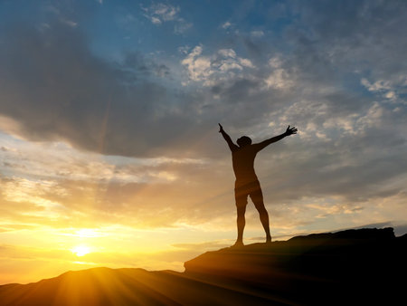 man on top of the mountain reaches for the sunの写真素材