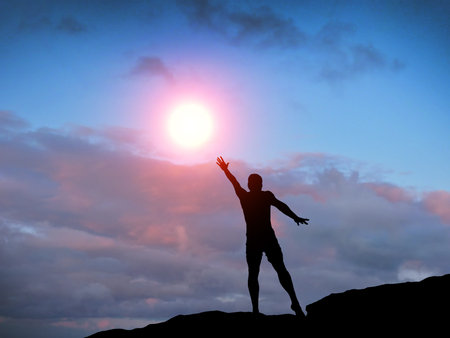 man on top of the mountain reaches for the sunの写真素材