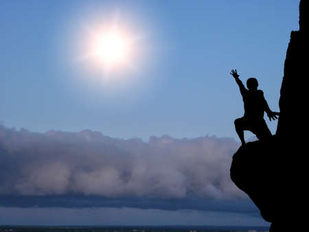 man on top of the mountain reaches for the sunの写真素材