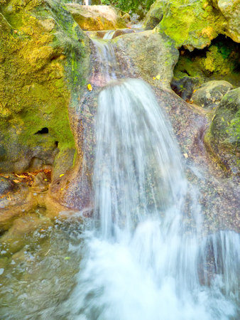 natural stream flows down the grassy stonesの写真素材