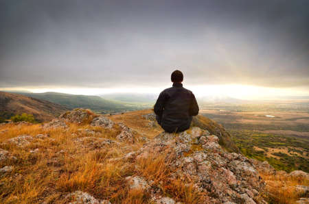 man on top of the mountain reaches for the sunの写真素材