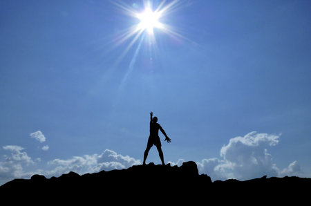 man on top of the mountain reaches for the sunの写真素材