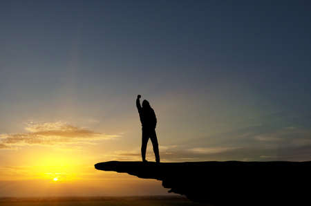 man on top of the mountain reaches for the sunの写真素材