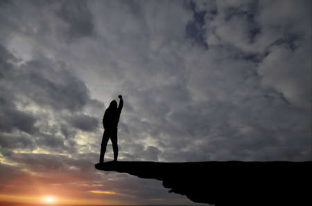 man on top of the mountain reaches for the sunの写真素材
