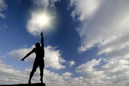 man on top of the mountain reaches for the sun
