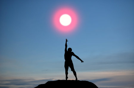 man on top of the mountain reaches for the sunの写真素材