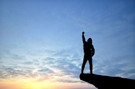 man on top of the mountain reaches for the sunの写真素材