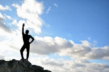 man on top of the mountain reaches for the sunの写真素材