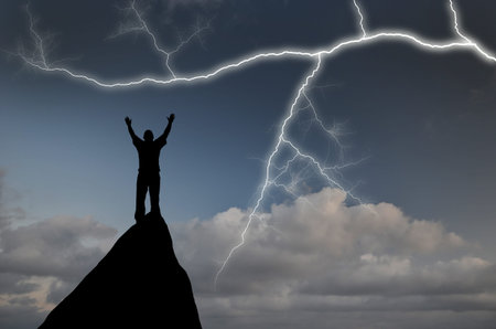 man on top of a mountain in the sky with bright lightningの写真素材