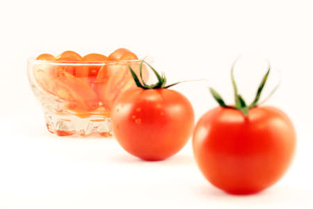 whole and sliced tomatoes in a dish on a white backgroundの写真素材