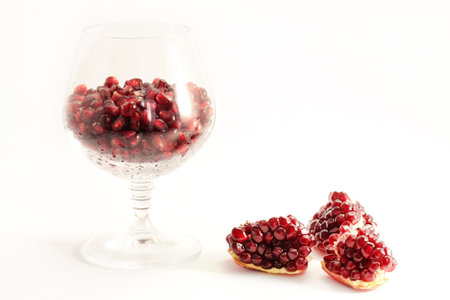 Pomegranate fruit arranged in a glass on a white background