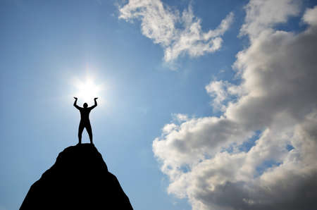 man on top of the mountain reaches for the sunの写真素材