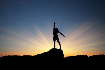 man on top of the mountain reaches for the sunの写真素材