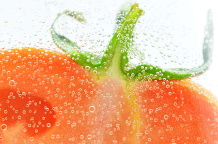 part of the tomato immersed in a liquid with bubblesの写真素材