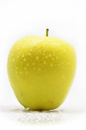 yellow apple with water droplets on the surface on a white backgroundの写真素材