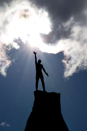 man on top of the mountain reaches for the sunの写真素材
