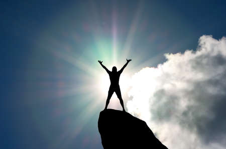 man on top of the mountain reaches for the sunの写真素材