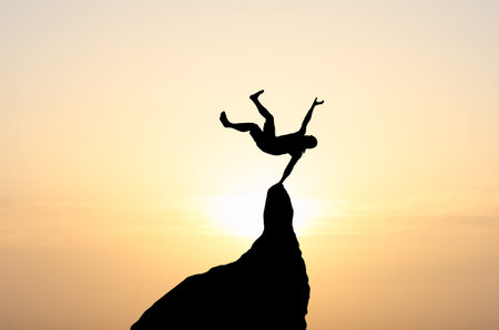 silhouette of a businessman with a laptop in hand is on top of a mountain in the sky with clouds.の写真素材