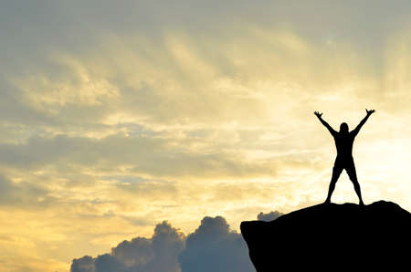 man on top of the mountain reaches for the sunの写真素材