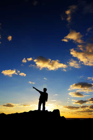 man on top of the mountain reaches for the sunの写真素材