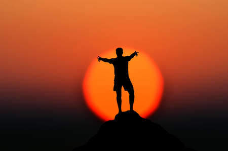 man on top of the mountain reaches for the sunの写真素材