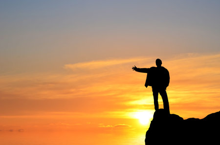 man on top of the mountain reaches for the sunの写真素材