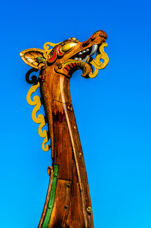 Dragon head on a replica Vking Ship with blue sky bakcground.