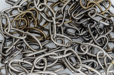 heavy pile of gray and bronze colored chains on a white background.