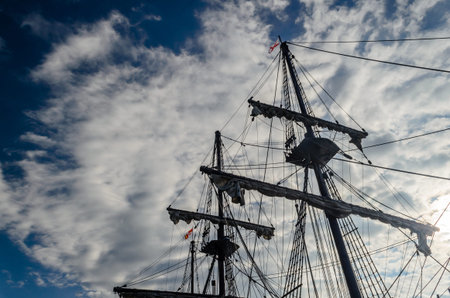 Upward view of tall ship rigging reaching up to a circular cloud above