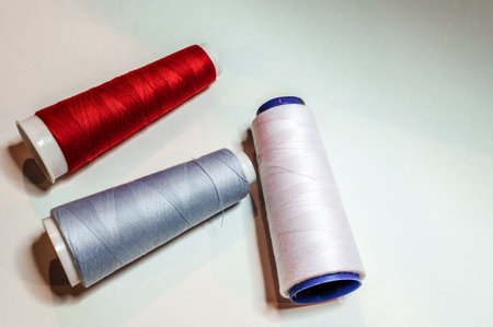 three large spools of red, blue and white thread laying on a white backkground