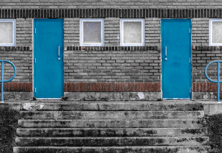 symmetrical Blue doors on the wall and stairs of a vintage building in black and white tone.