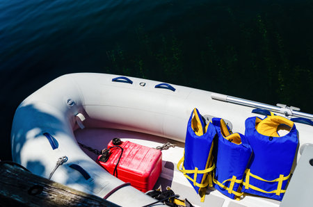 White dinghy, with gasoline can and blue and ywllow life jackets floating at the edge of a dock in the Thousand Islands, on the St. Lawrence Riverの写真素材