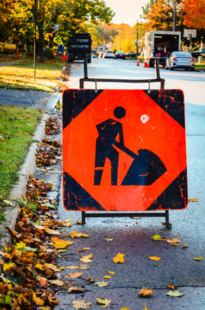 Close-up of a road construction sign with work in the background on a fall morningの写真素材