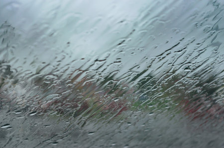 Abstract view with raindrops flowing diagonally across a windshield with muted color.patterns.