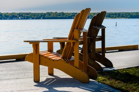 Two Adirondack chairs facing left at water's edge on the St. Lawrence River