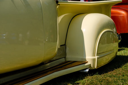 Yellow customized antique pickup truck close-up side view showing fender skirt