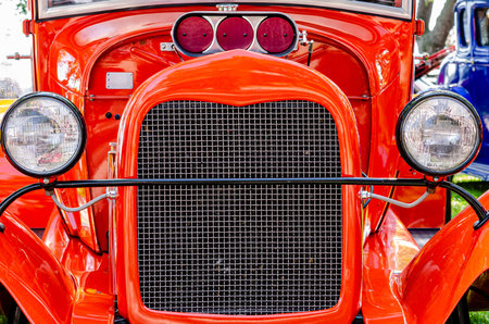 Symmetrical Front view of a red hot rod with grill, headlights and supercharger intake.