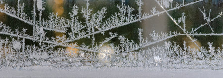 Panorama of window ice crystal pattern against a dark background with lens flare