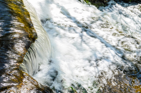 Close-up of a water cascading in a stream creating frothy water.の写真素材