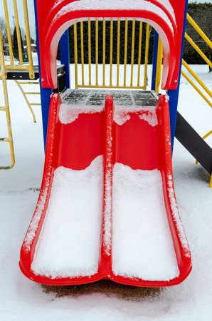 Red slide empty residential playground in the snowの写真素材