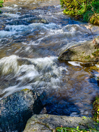 Close-up of whitewater stream flowing fast around rocksの写真素材